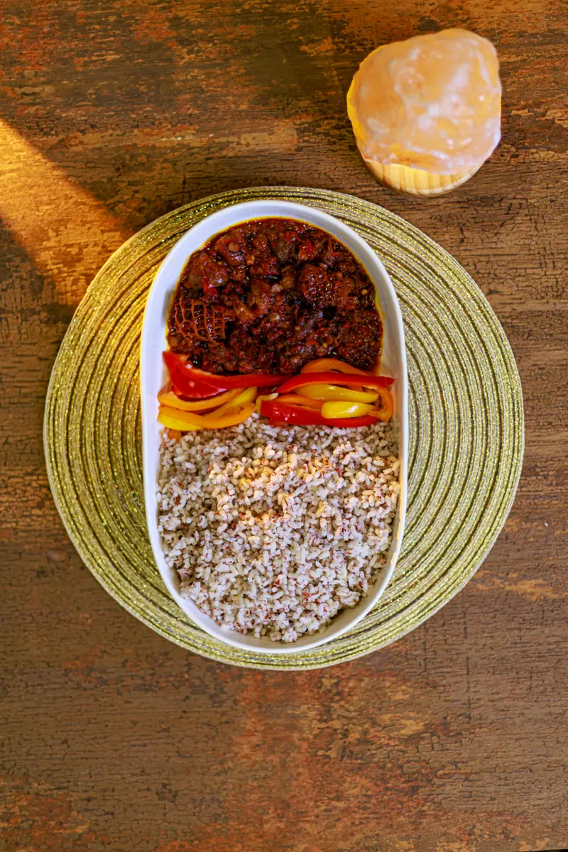 Ofada rice served with ayamase, meat and egg